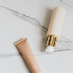 Brown Cream Tube and Pump Bottle on White Surface